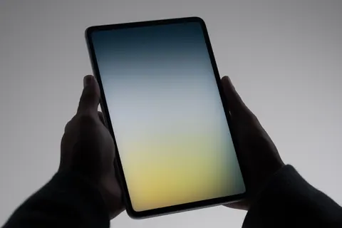 Hands holding a tablet displaying a gradient interface
